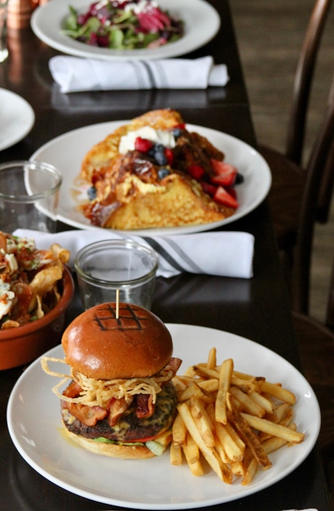 Plate with a burger and fries on a restaurant table alongside other dishes