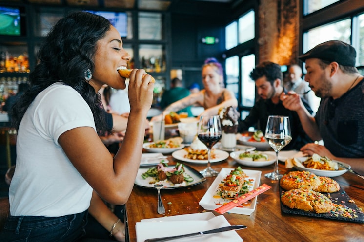 People dining together at a restaurant table with various dishes and drinks
