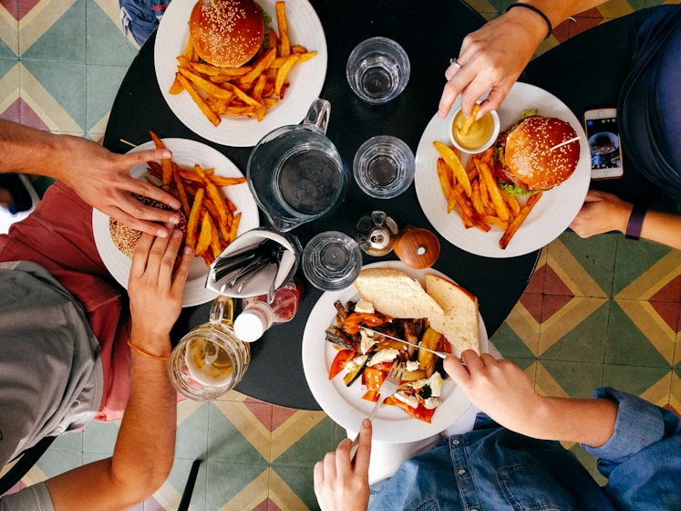 Overhead view of four people eating burgers and fries at a round table
